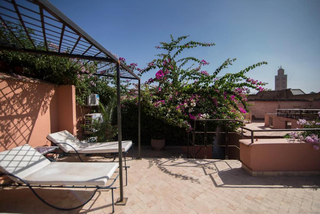 - une terrasse avec 2 chaises et des fleurs dans un bâtiment dans l'établissement Riad Palais Sebban, à Marrakech