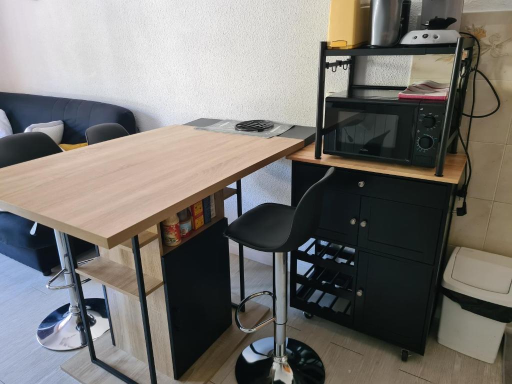 Elle comprend un bureau avec un four micro-ondes et une table avec une chaise. dans l'établissement Agréable appartement-Résidence Le Panoramic, aux Angles 6 autres photos