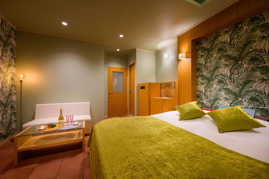 une chambre avec un grand lit avec une couverture verte dans l'établissement ハッピーキス双葉店, à Kai