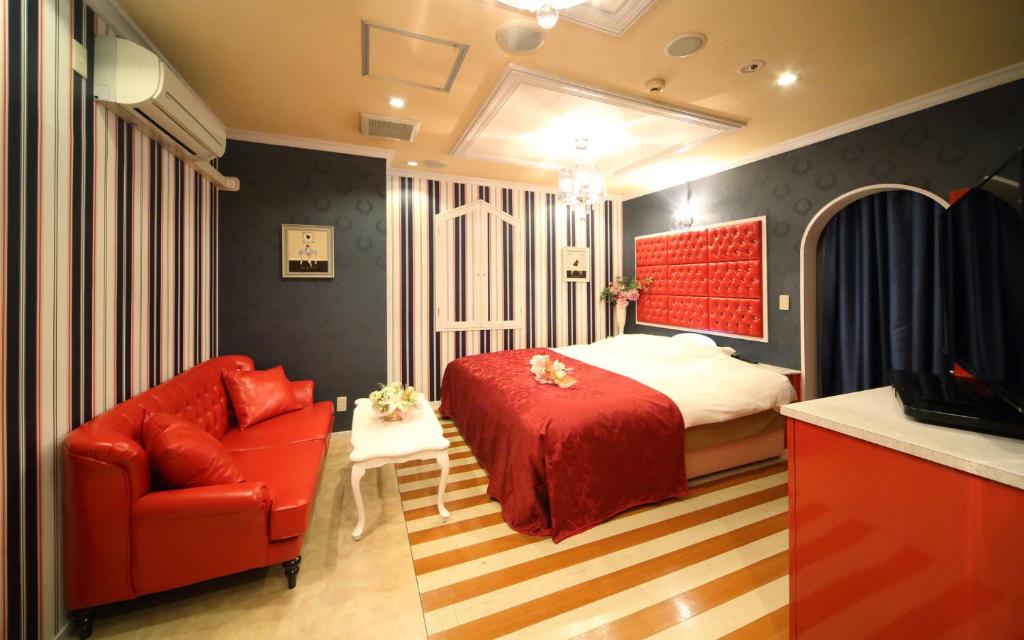 - une chambre avec un lit rouge et une chaise rouge dans l'établissement ホテル フェアリー岩槻 Adult only, à Saitama