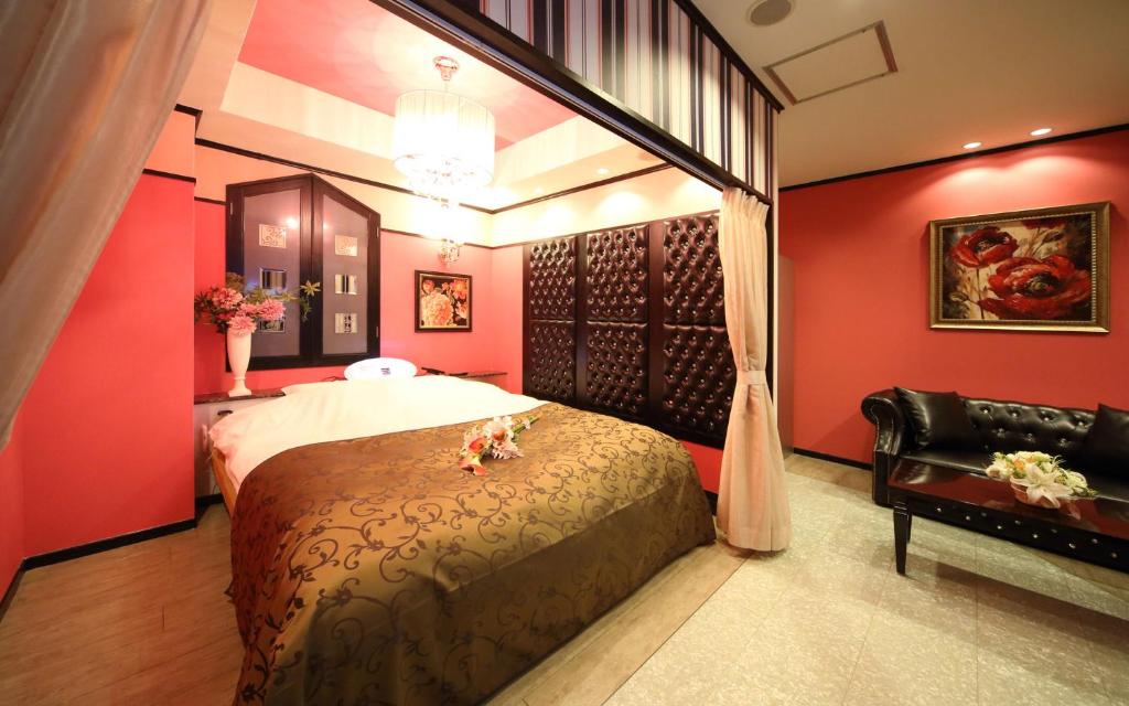 une chambre avec des murs rouges et un lit et un canapé dans l'établissement ホテル フェアリー岩槻 Adult only, à Saitama