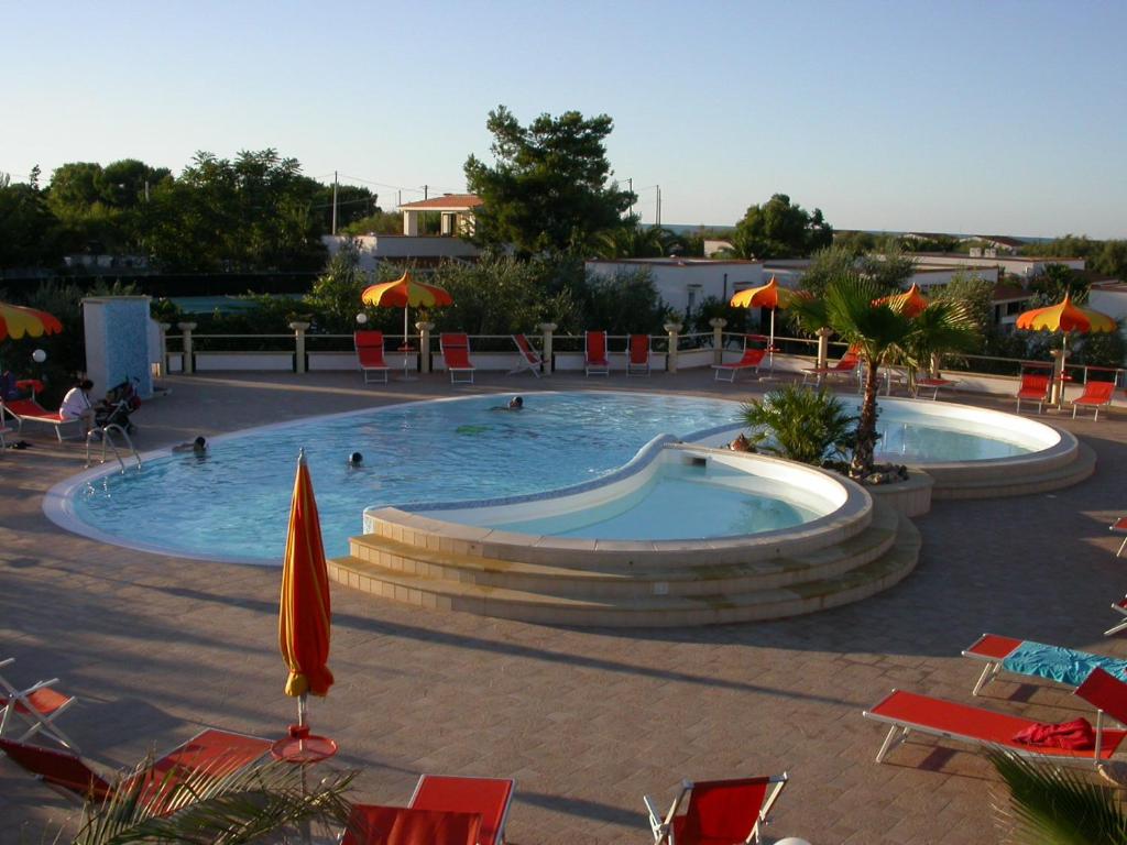 une grande piscine avec chaises et parasols dans l'établissement Residence Sun Bay, à Vieste