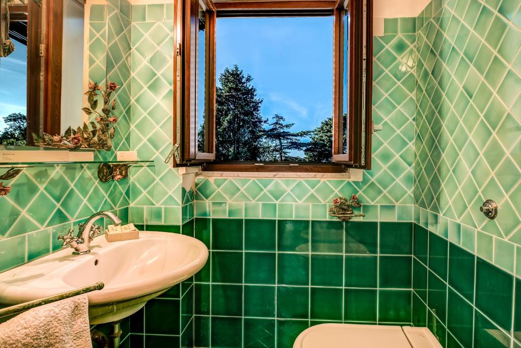 - une salle de bains carrelée de vert avec lavabo et fenêtre dans l'établissement Villa Demetra Capri - Pool and Relaxation, à Anacapri