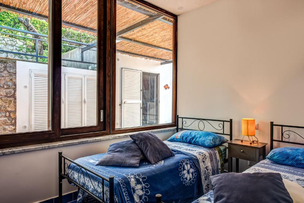 deux lits dans une chambre avec deux fenêtres dans l'établissement Villa Demetra Capri - Pool and Relaxation, à Anacapri