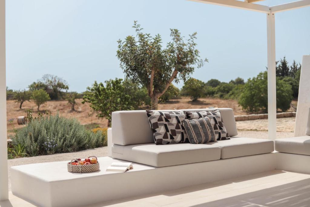 un canapé blanc avec un panier de fruits sur une terrasse dans l'établissement TD I Coni di Pinurè Trulli with Scenic Valley View, à Martina Franca
