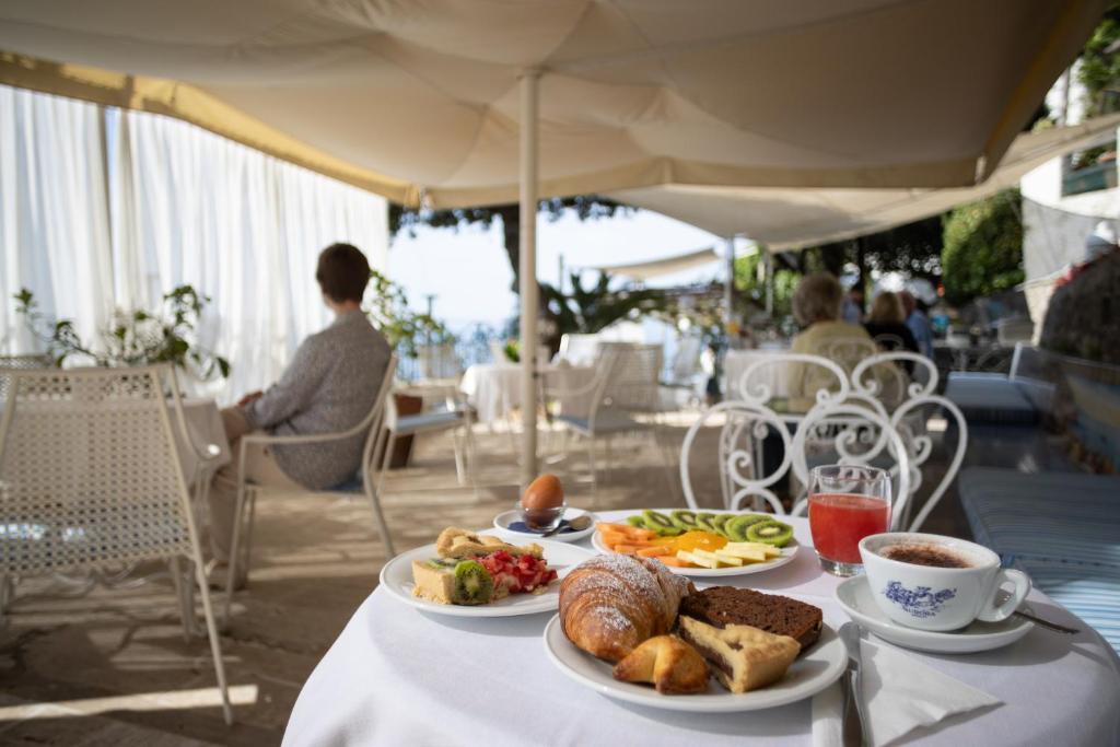 une table avec deux assiettes de nourriture et une tasse de café dans l'établissement Hotel Aurora, à Amalfi