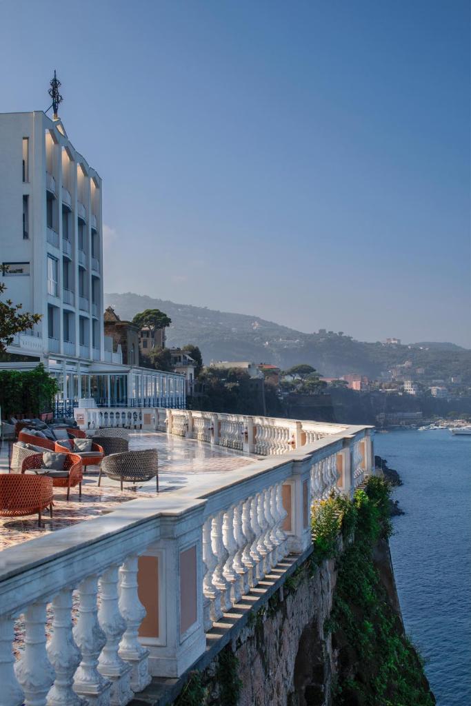 d'un balcon avec des chaises et d'un bâtiment au bord de l'eau. dans l'établissement Parco dei Principi, à Sorrente