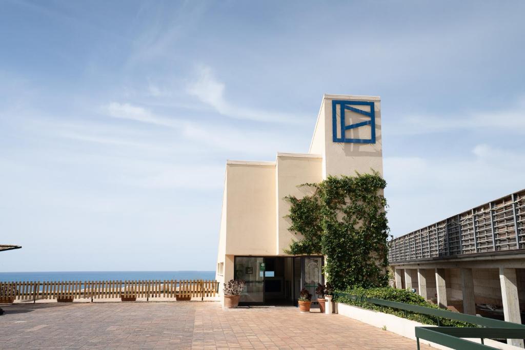 un bâtiment avec une tour d'horloge à côté de l'océan dans l'établissement Grand Hotel San Pietro, à Palinuro