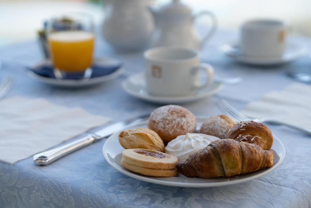 une assiette de pâtisseries sur une table avec une tasse de café dans l'établissement Grand Hotel San Pietro, à Palinuro
