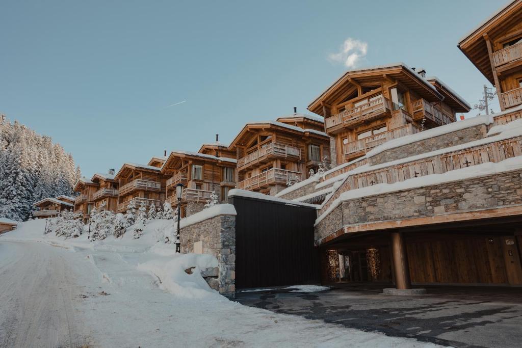 une rangée de bâtiments en bois dans la neige dans l'établissement Ultima Hotel Courchevel, à Courchevel