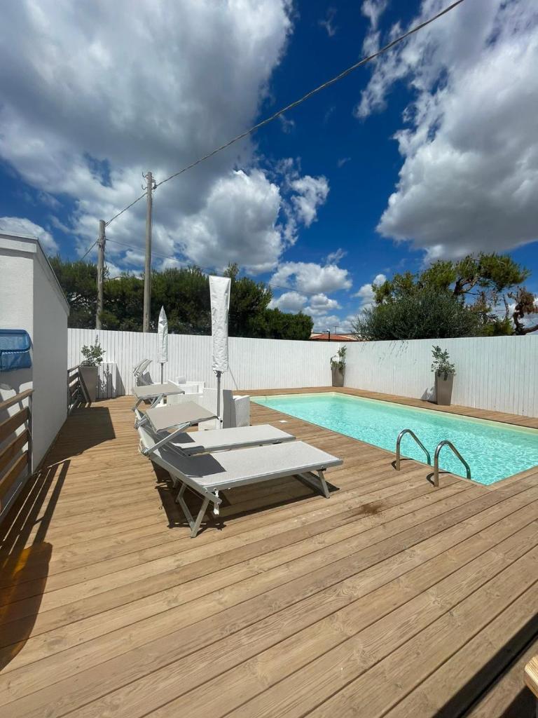 une piscine avec des chaises et une terrasse en bois dans l'établissement Maracaibo Village, à Tarente