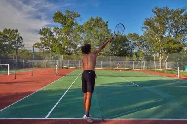 un homme sans navire tenant une raquette de tennis sur un court de tennis dans l'établissement Iscles 231- MH Au calme près du lac, à La Roque-dʼAnthéron