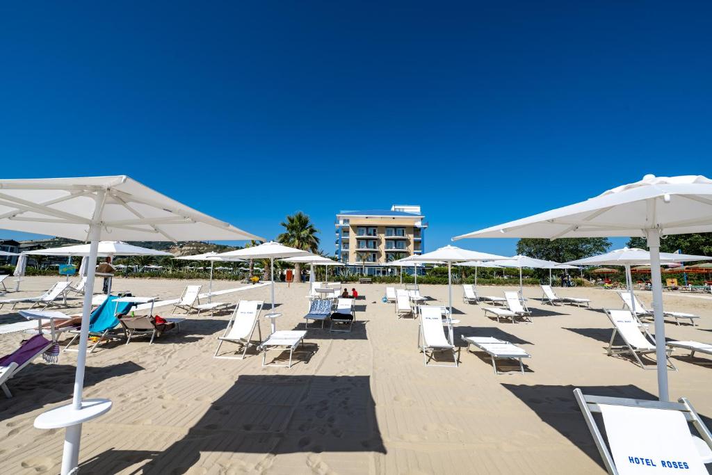 - un bouquet de chaises et de parasols sur une plage dans l'établissement Roses Hotel, à Roseto degli Abruzzi