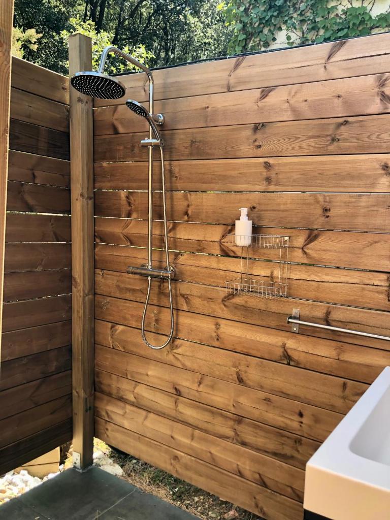 La salle de bains est pourvue d'une douche et d'un mur en bois. dans l'établissement glamping Bonheur, à Arles-sur-Tech