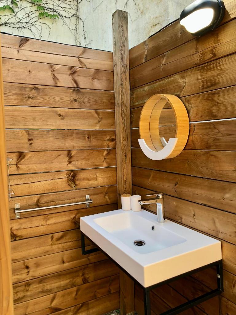 La salle de bains est pourvue d'un lavabo et d'un mur en bois. dans l'établissement glamping Bonheur, à Arles-sur-Tech