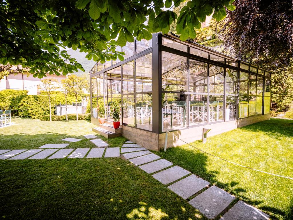 une serre en verre dans une cour avec de l'herbe dans l'établissement Domus Plinii 1792 Suites, à Faggeto Lario