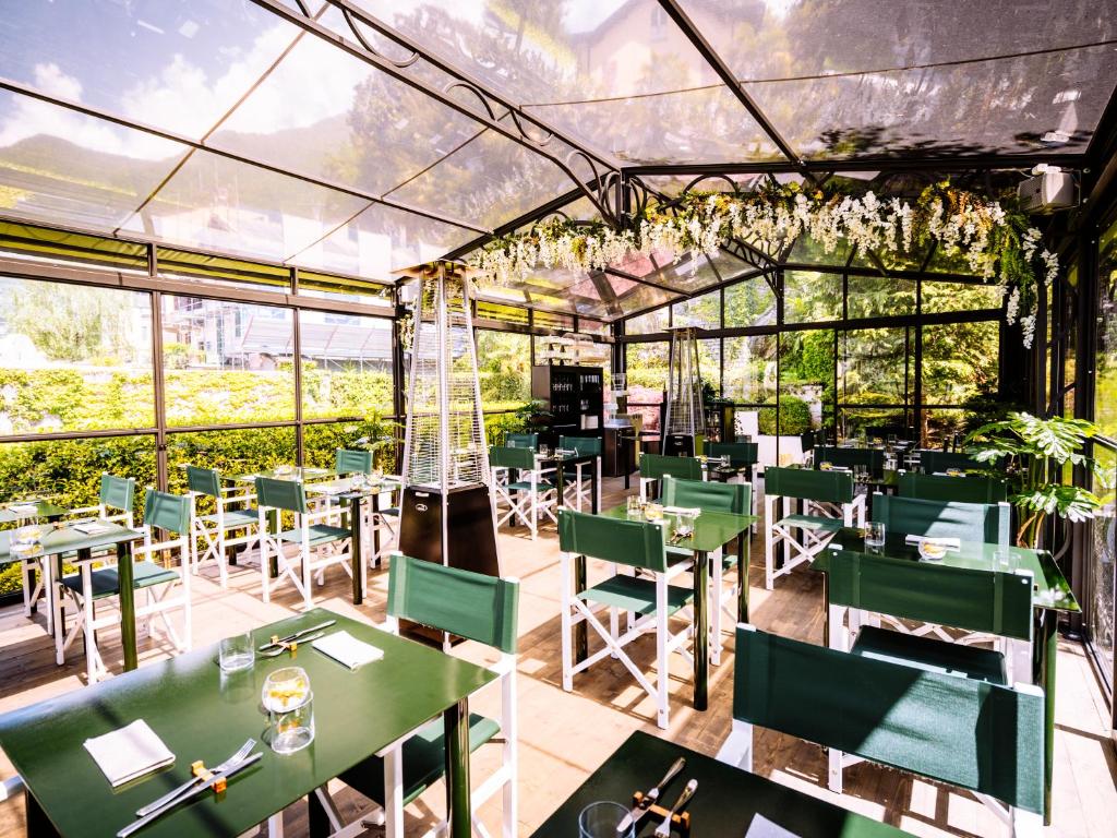 un restaurant avec des tables vertes, des chaises et des fenêtres dans l'établissement Domus Plinii 1792 Suites, à Faggeto Lario