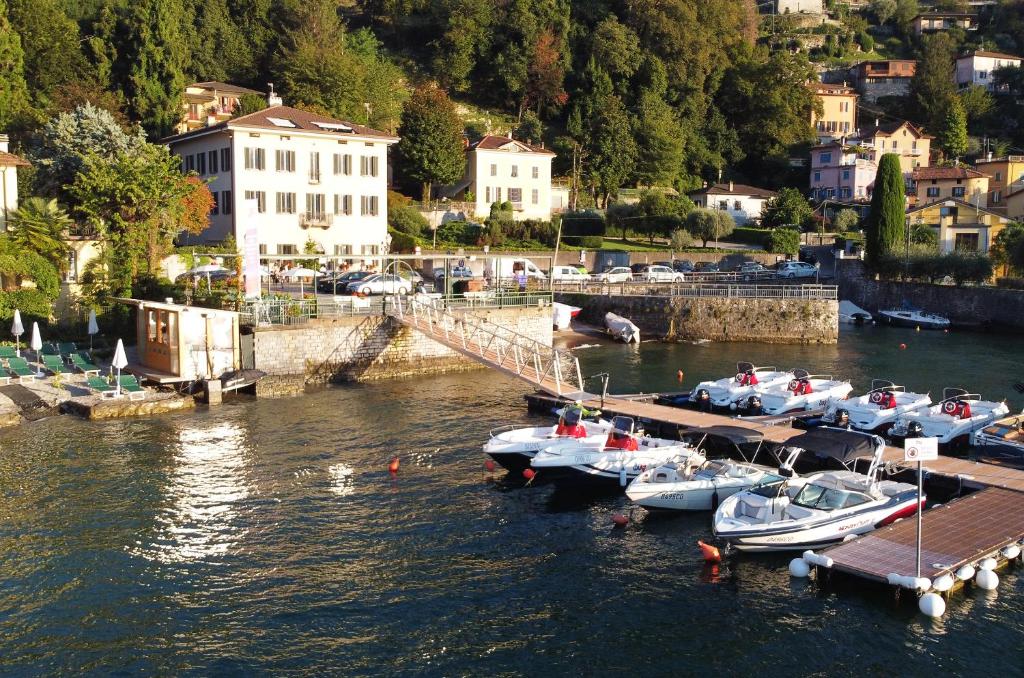 un groupe de bateaux amarrés à un quai dans l'eau dans l'établissement Domus Plinii 1792 Suites, à Faggeto Lario
