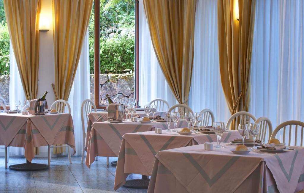 une salle à manger avec des tables et des chaises et des rideaux jaunes dans l'établissement Hotel San Giovanni Terme, à Ischia