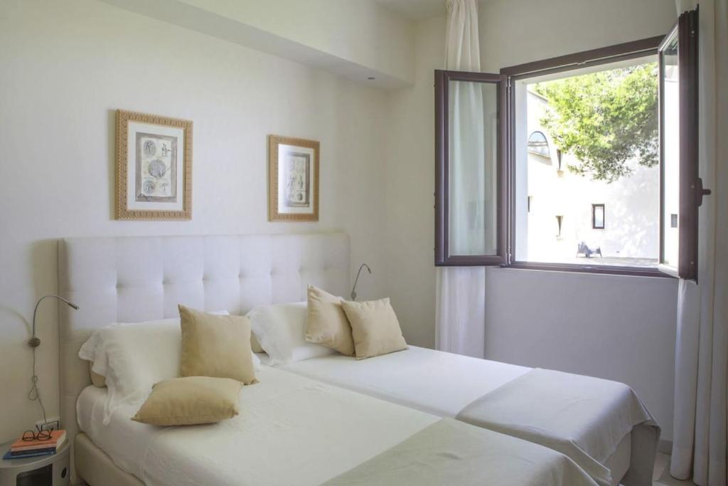 un lit blanc dans une chambre avec une fenêtre dans l'établissement Masseria Ceratonia by Raro Villas, à Baia Verde