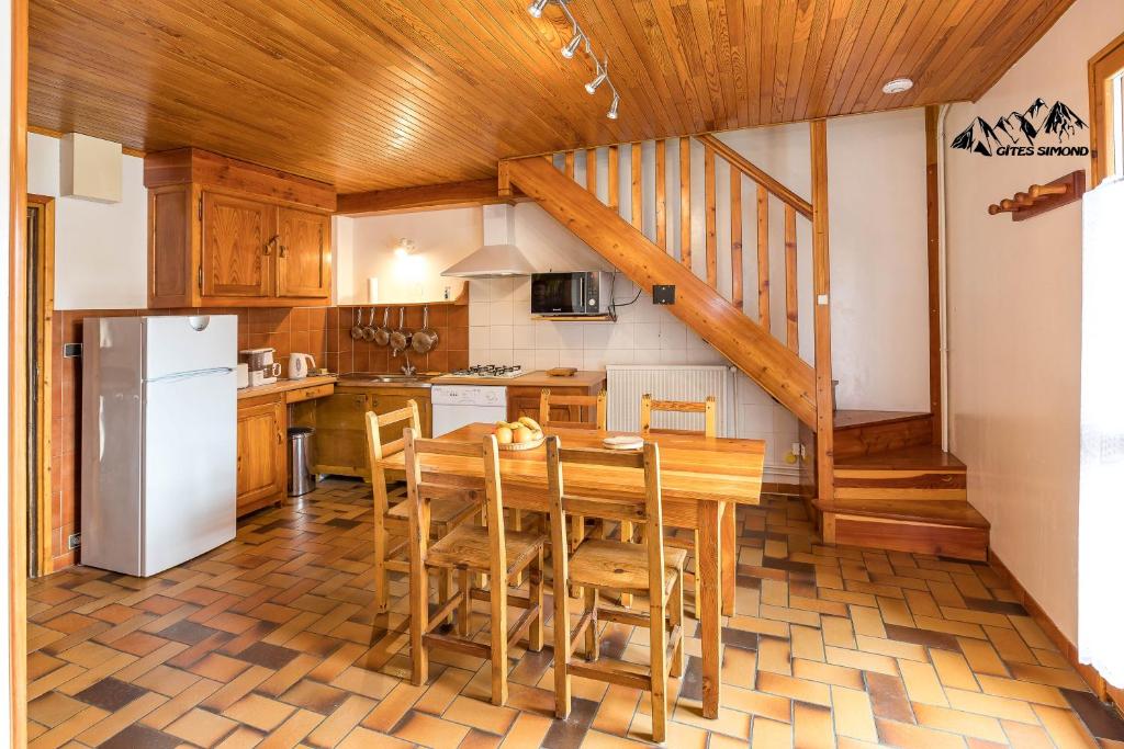 une cuisine avec une table et des chaises ainsi qu'un escalier dans l'établissement Gîtes Simond, à Arvieux