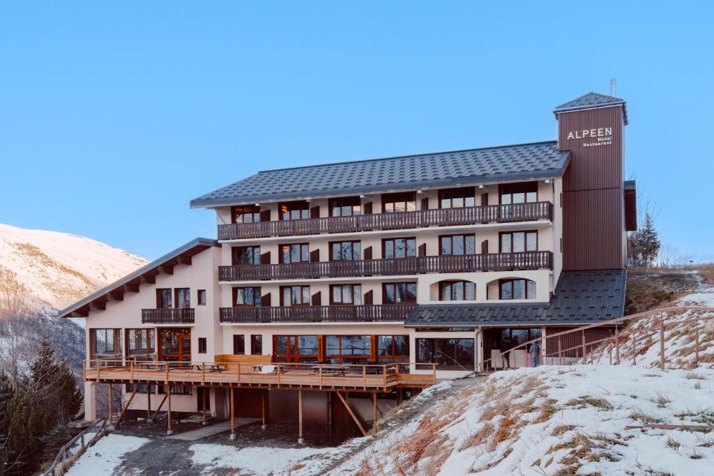un grand bâtiment au sommet d'une colline enneigée dans l'établissement Alpeen Hotel, aux Menuires