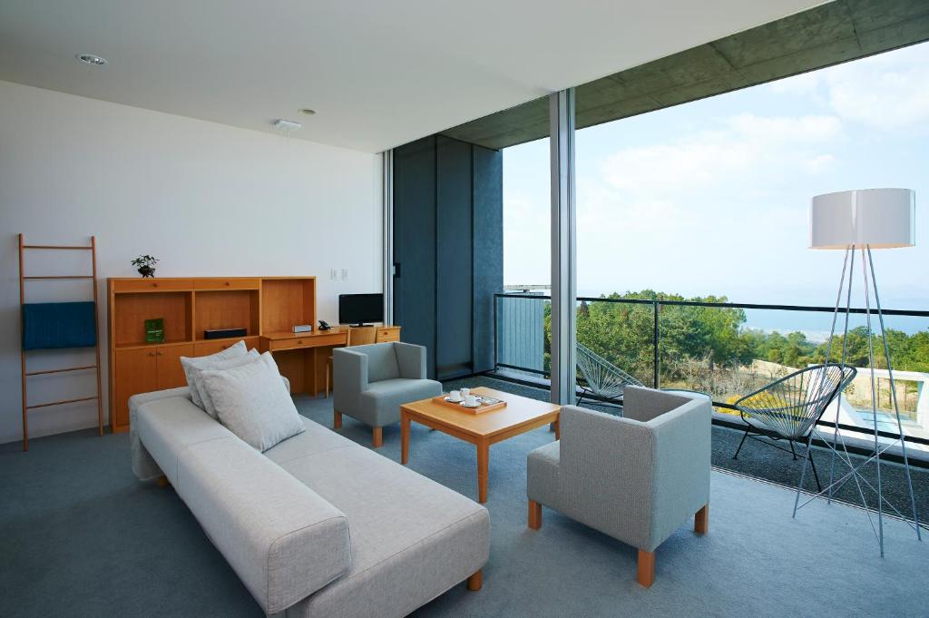 un salon avec un canapé et des chaises et une grande fenêtre dans l'établissement SETOUCHI RETREAT by Onko Chishin, à Matsuyama