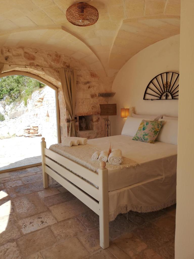 une chambre avec un lit dans une pièce avec une fenêtre dans l'établissement Eremo di San Giusto - Trullo Vista Mare, à Ostuni