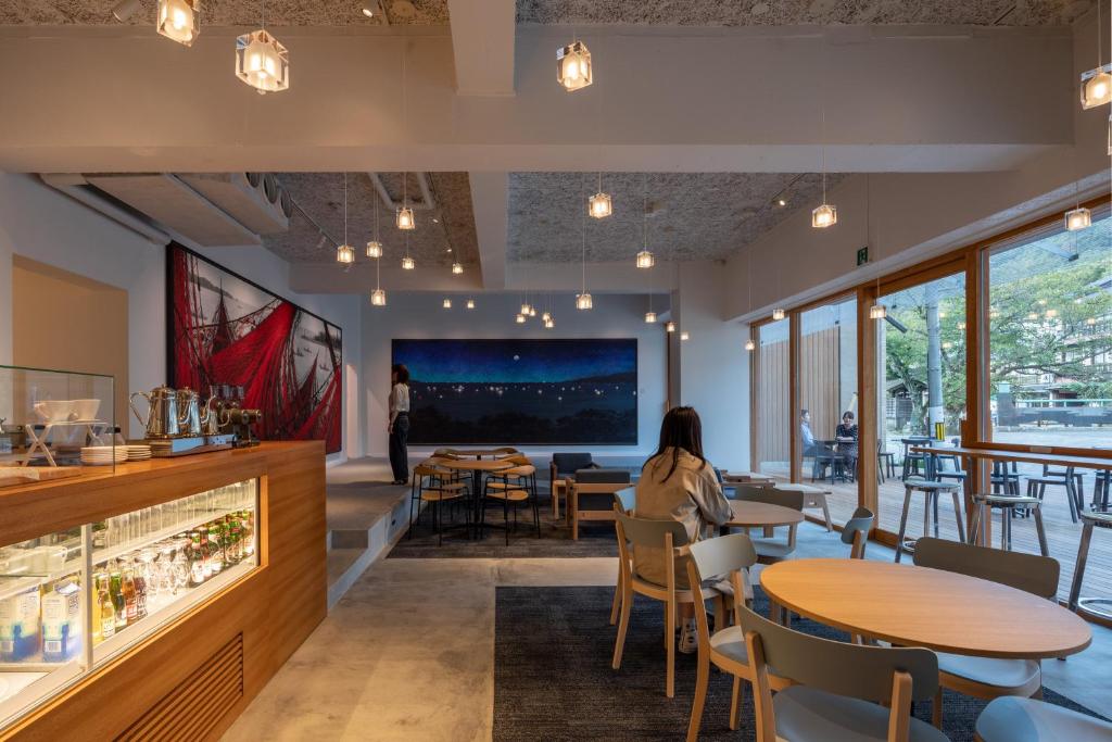 une salle à manger avec des tables, des chaises et un grand écran dans l'établissement TSUCHIYA Kinosaki onsen, à Toyooka