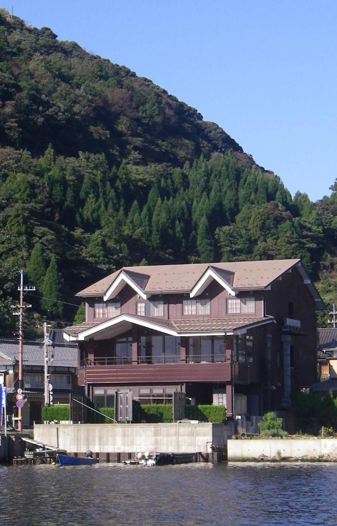 un grand bâtiment sur l'eau à côté d'une montagne dans l'établissement 湖上館パムコ, à Wakasa