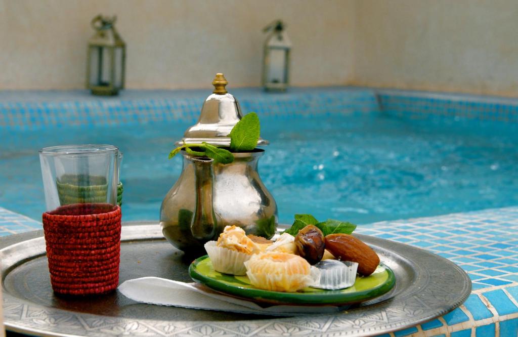 une assiette de nourriture sur une table à côté d'une piscine dans l'établissement Riad Vert, à Marrakech