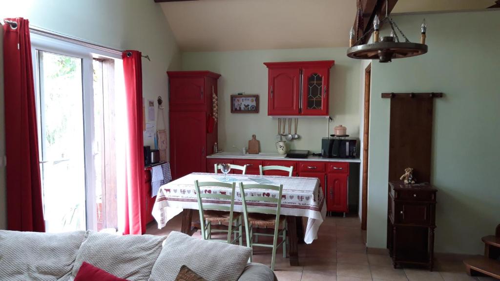 une cuisine avec des placards rouges et une table avec des chaises dans l'établissement la vallee du cher, à Monthou-sur-Cher