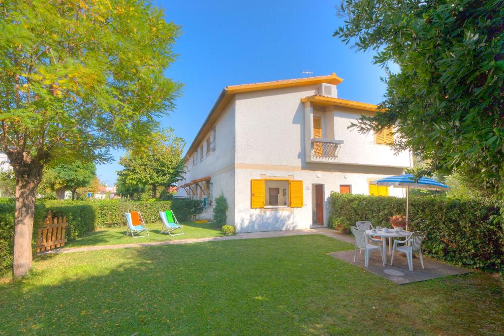 une maison avec une cour dotée de chaises et d'un parasol dans l'établissement Villaggio Turistico Internazionale, à Porto Recanati