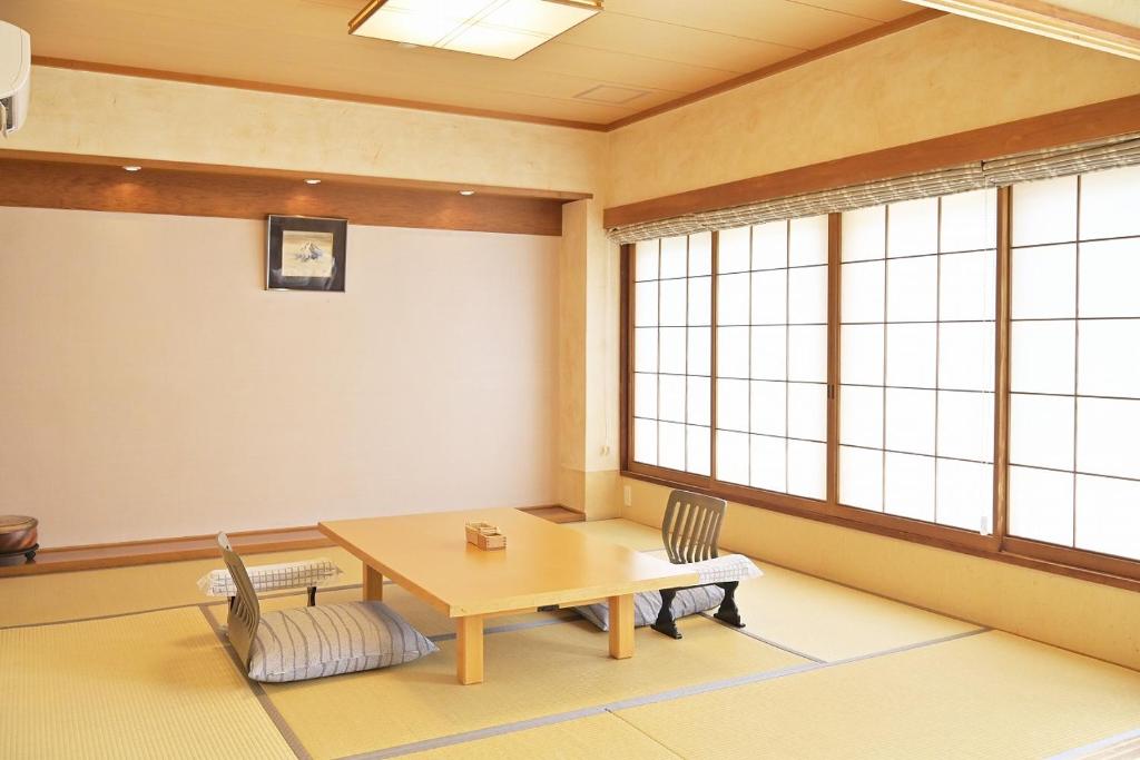 une pièce avec une table, des chaises et des fenêtres dans l'établissement Kansuitei Kozeniya, à Tottori