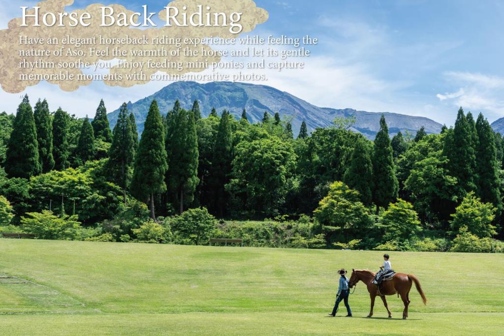 deux personnes à cheval dans un champ dans l'établissement KAMENOI HOTEL Aso, à Aso