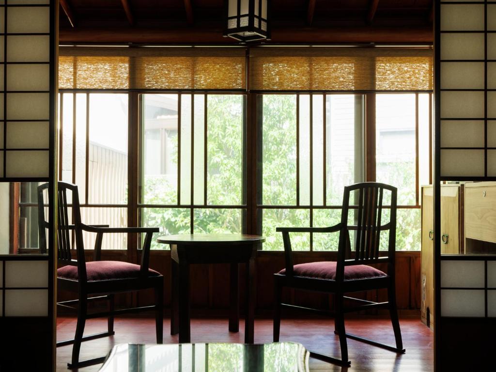 une table et des chaises dans une pièce avec des fenêtres dans l'établissement Machi no Odoriba, à Kanazawa