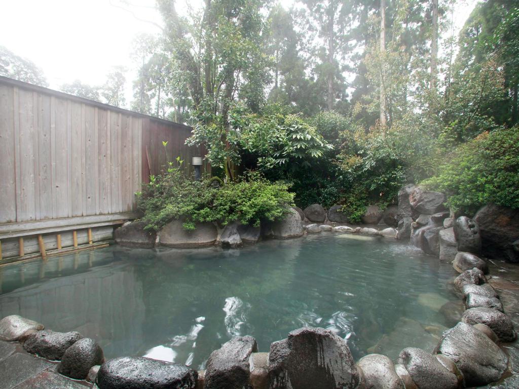 un bassin d'eau à côté d'une clôture en bois dans l'établissement Hotel Kirishima Castle, à Kirishima
