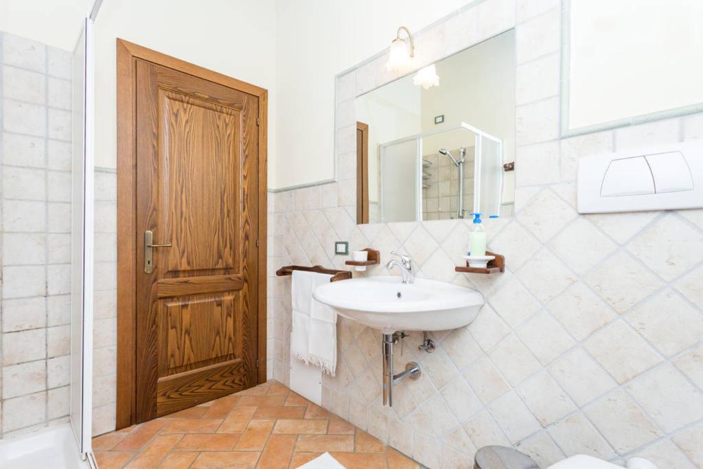 La salle de bains est pourvue d'un lavabo et d'une porte en bois. dans l'établissement La Casa Del Sole, à Casamaggiore