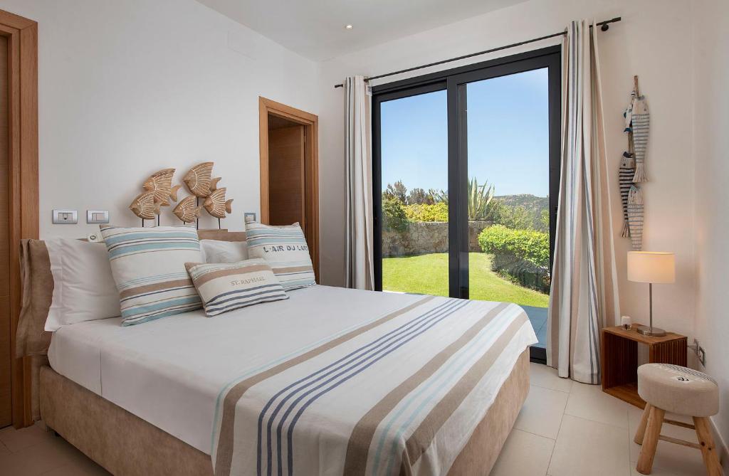 une chambre avec un lit et une grande fenêtre dans l'établissement Villa Marita Luxury Sea View Chia, à Santa Margherita di Pula