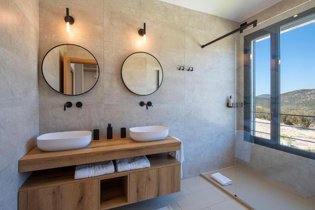 une salle de bain avec deux lavabos et deux miroirs dans l'établissement Villa Marita Luxury Sea View Chia, à Santa Margherita di Pula