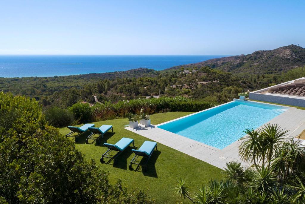 une piscine avec des chaises et l'océan en arrière-plan dans l'établissement Villa Marita Luxury Sea View Chia, à Santa Margherita di Pula