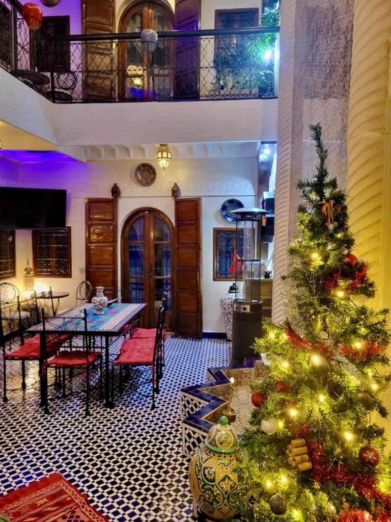 un sapin de Noël dans une pièce avec une table et des chaises dans l'établissement Riad Lalla Merieme, à Marrakech