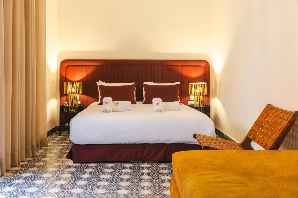 une chambre avec un grand lit blanc et une chaise dans l'établissement Riad JW Yacout, vivez l'expérience Medina, à Marrakech