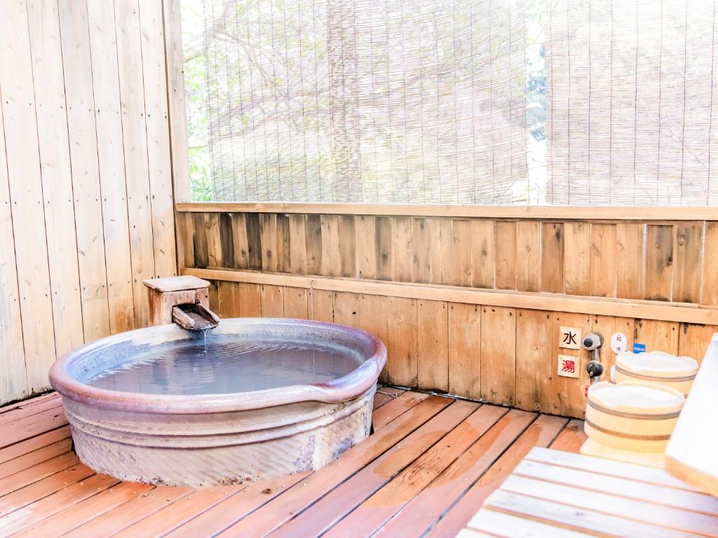 La salle de bains en bois est pourvue d'une grande baignoire et de toilettes. dans l'établissement Kirishima Momijidani Seiryuso, à Kirishima