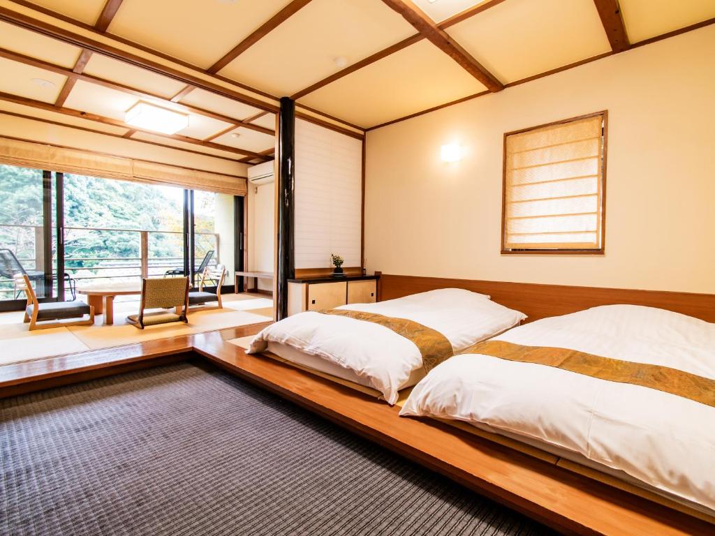 deux lits dans une chambre avec un cadre de lit en bois dans l'établissement Kirishima Momijidani Seiryuso, à Kirishima 37 autres photos