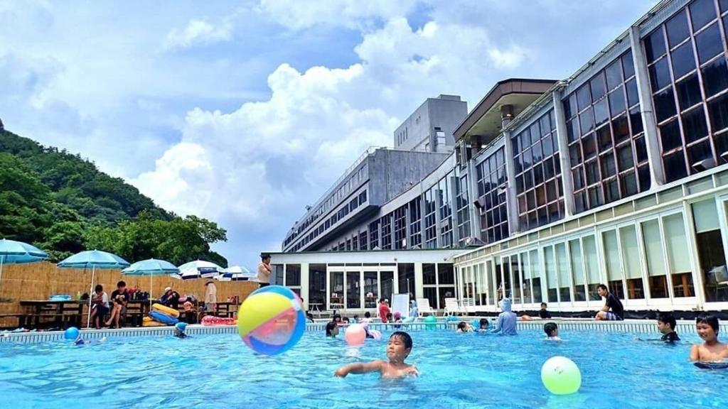 - un groupe de personnes dans une piscine avec un ballon de plage dans l'établissement Okudogo Ichiyunomori, à Matsuyama