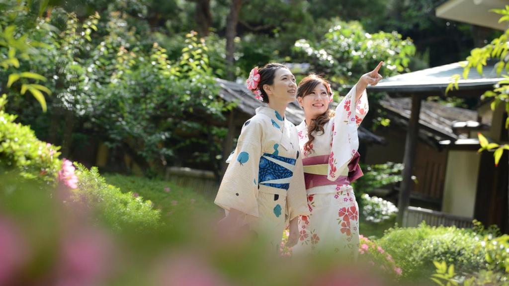 Deux femmes en kimonos debout dans un jardin dans l'établissement Okudogo Ichiyunomori, à Matsuyama
