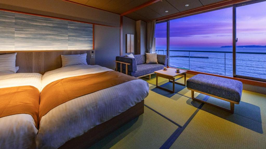 une chambre avec un lit et une vue sur l'océan dans l'établissement Hanashibuki, à Tateyama