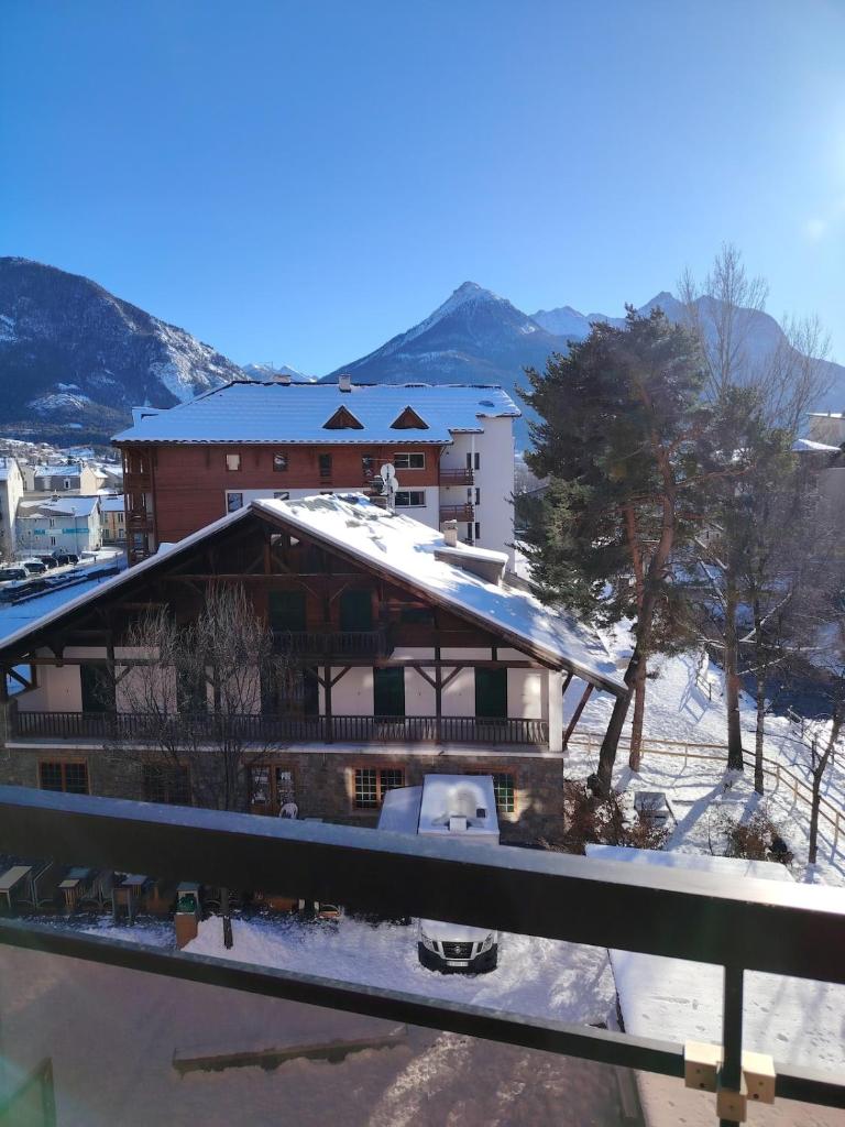 une maison avec de la neige sur le toit dans l'établissement Bel appartement au pied des pistes de serre chevalier, à Briançon
