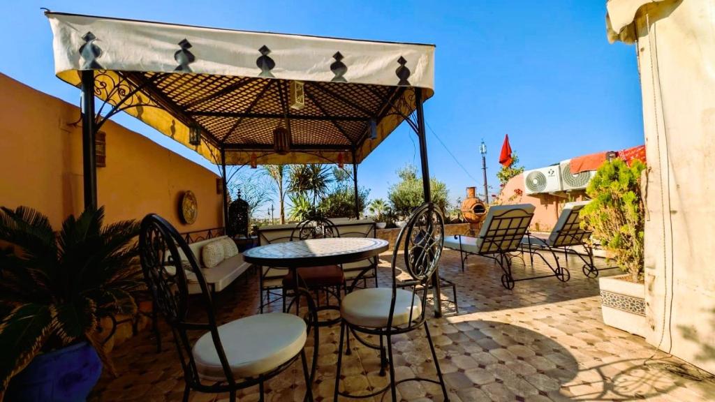 une terrasse avec des chaises, une table et un parasol dans l'établissement Riad Lalla Merieme, à Marrakech